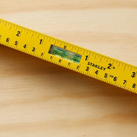 A close-up of the STANLEY 42-328 Heavy Duty Aluminum I-Beam Level with a rotating vial for precision leveling on a wooden surface, featuring both inches and centimeters.