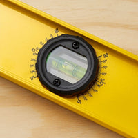 Close-up of the STANLEY 42-328 48 in. Heavy Duty Aluminum I-Beam Level, featuring a yellow design and a circular 180-degree rotating vial for balance, with angle markings from 0 to 90 degrees for precision against a wooden surface.