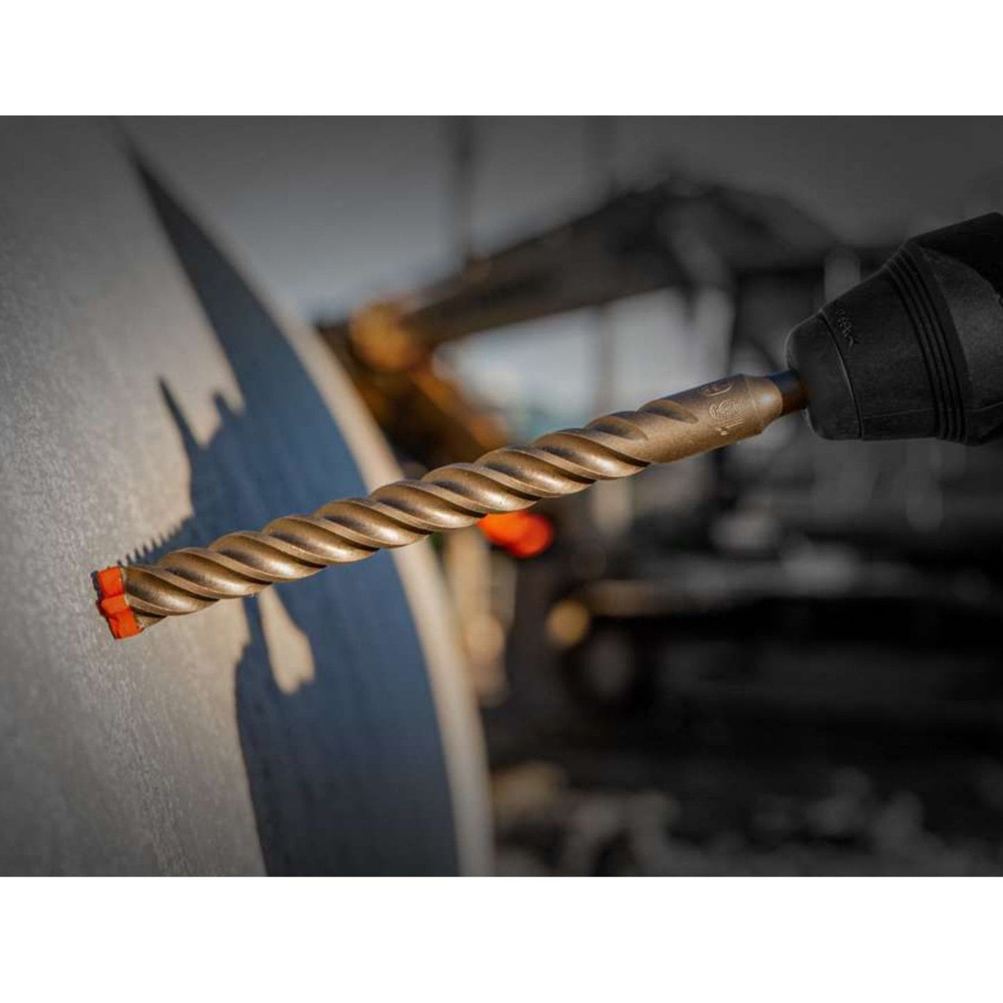 A close-up shows the Diablo DMAPL4040 Rebar Demon™ SDS-Plus drill bit with its twisted design cutting into concrete, highlighting its industrial strength and precision against a blurred background.