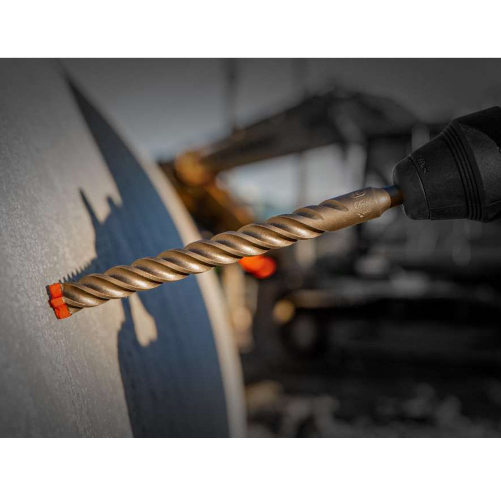 A close-up shows the Diablo DMAPL4040 Rebar Demon™ SDS-Plus drill bit with its twisted design cutting into concrete, highlighting its industrial strength and precision against a blurred background.