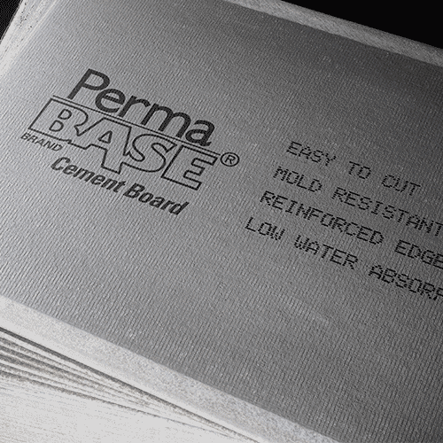 Close-up of a stack of PERMABASE 3 ft. x 5 ft. Cement Boards with EdgeGuard, showcasing text that highlights features like easy cutting, mold resistance, reinforced edges, and low water absorption—ideal for tiling projects.