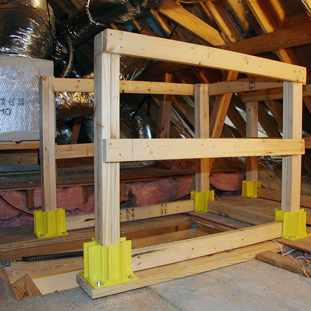 Yellow Safety Maker Safety Boot Guardrails by Go Build, the Fastest Way to Build, are like construction site guardrails with yellow safety boot bases, installed around an open attic hatch amid insulation, ductwork, and wooden beams.